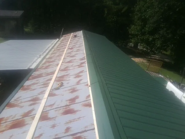 Old rusted panels beside newly installed green metal roofing — Wind Damage Roof Repair by Roofing Brothers in Essig