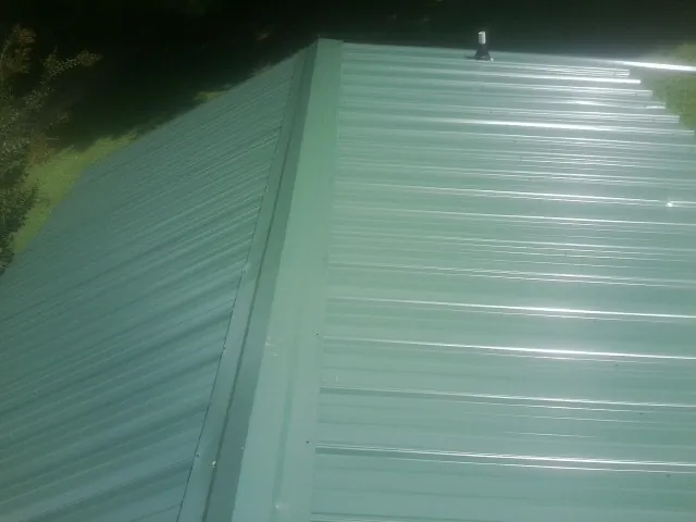 New green metal panels meeting at the ridge of a roof — Flat Roof Repair work by our crew in Essig
