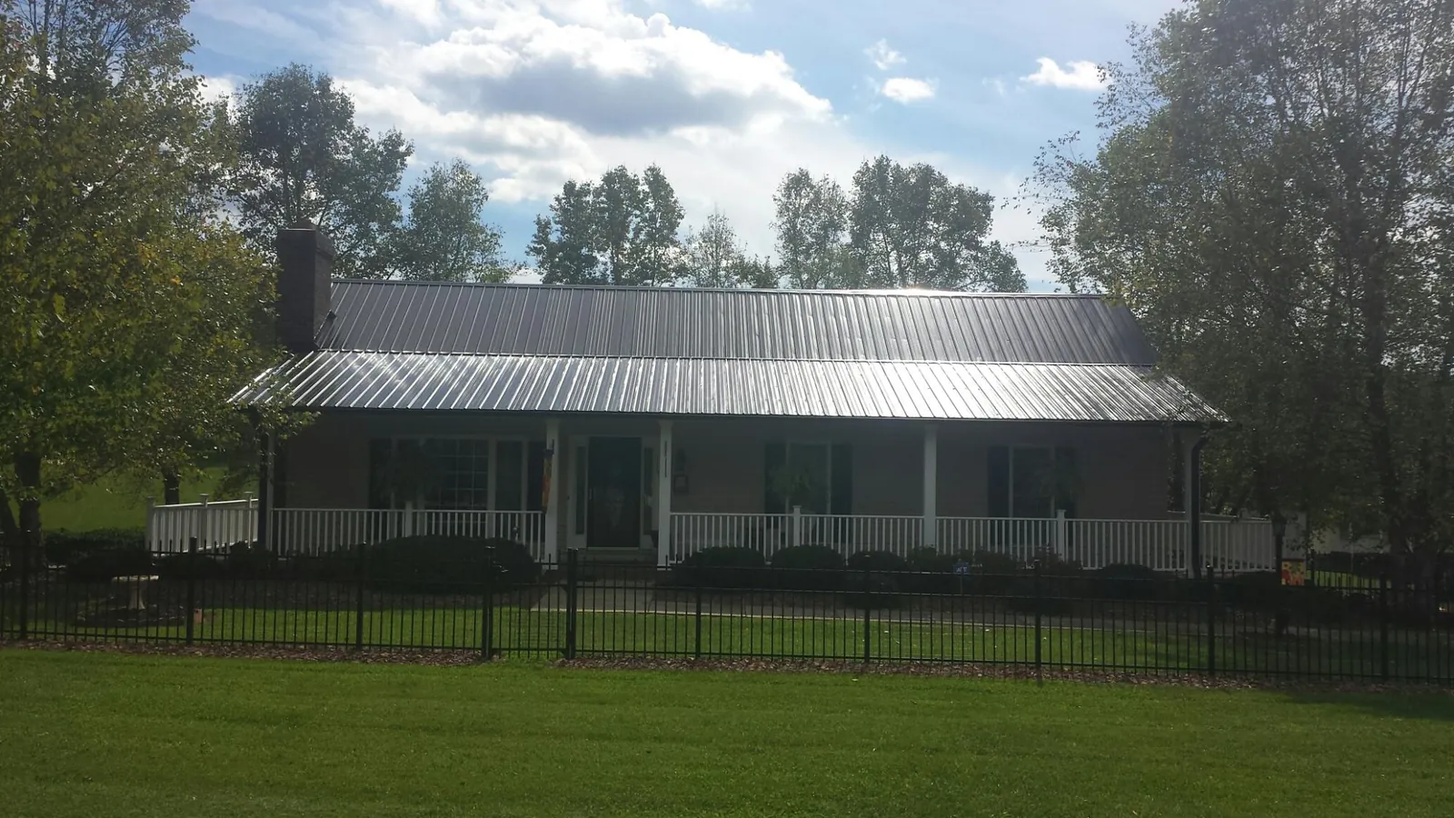 Gray metal roof on a brick ranch with a full width front porch — Gutter Guard Installation work by our crew in Essig