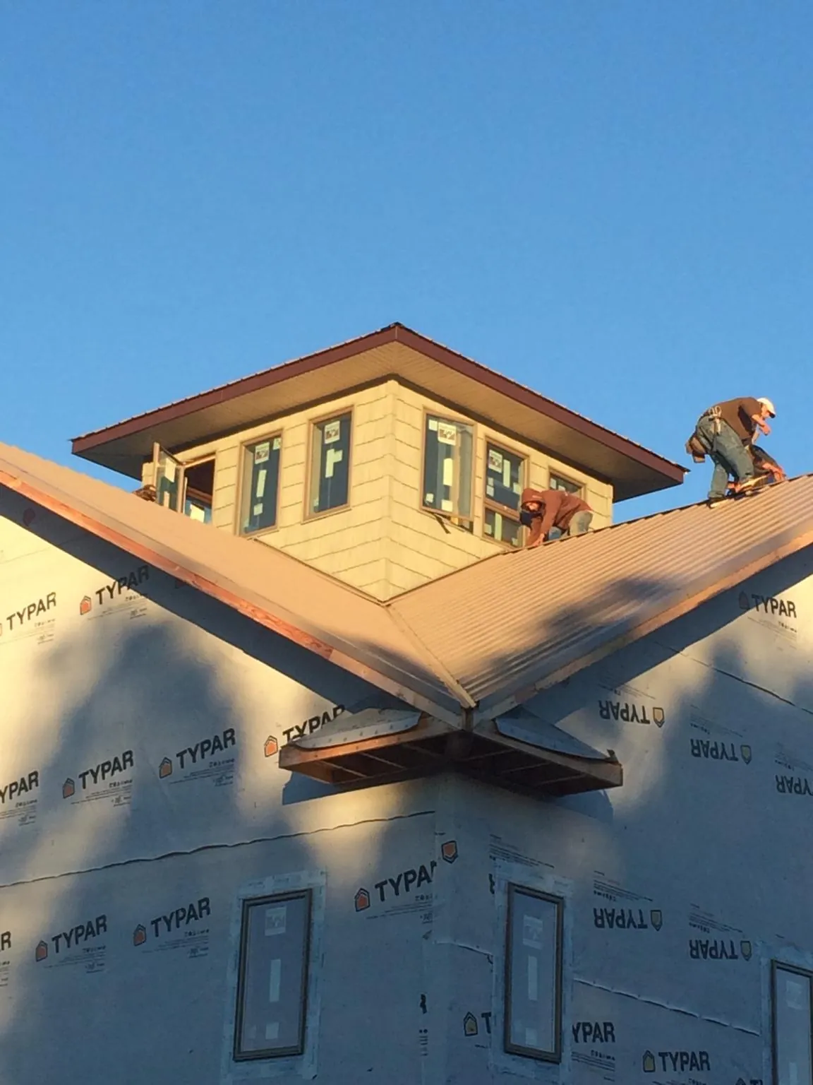 Roofers working around a rooftop cupola on a new metal roof at sunset — Roof Waterproofing in Essig by Roofing Brothers